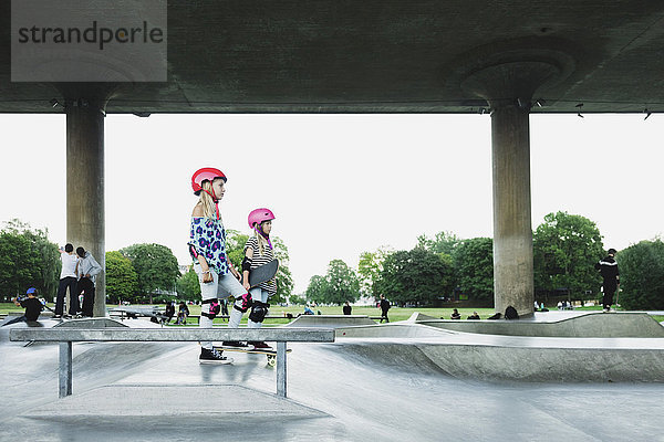 Seitenansicht von Freunden  die am Skateboard-Park gegen den klaren Himmel stehen.