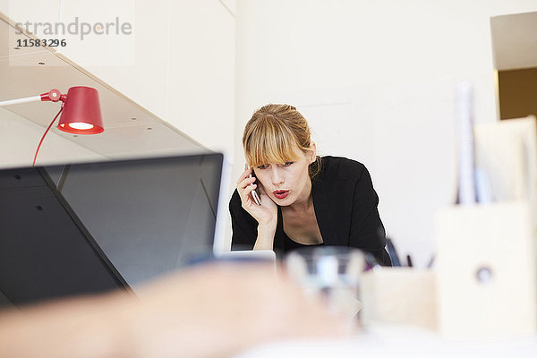 Mittlere erwachsene Geschäftsfrau beim Telefonieren im Büro