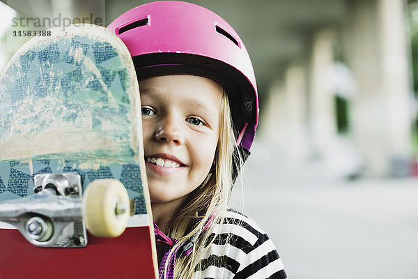 Portrait des glücklichen Mädchens mit Skateboard im Park