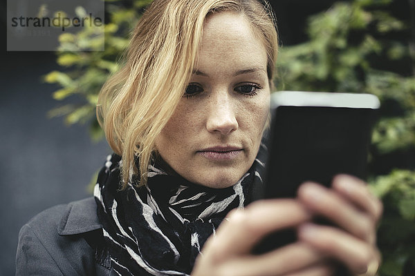 Mittlere erwachsene Geschäftsfrau mit Smartphone im Freien