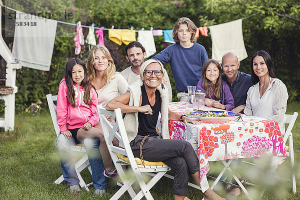 Porträt der glücklichen Familie und Freunde im Garten während der Gartenparty