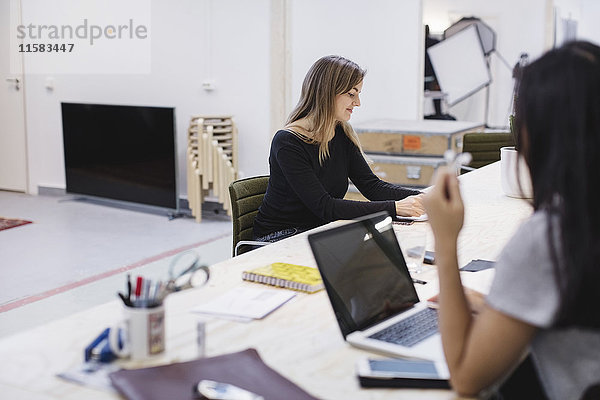 Zwei junge Frauen arbeiten am Schreibtisch im Kreativbüro