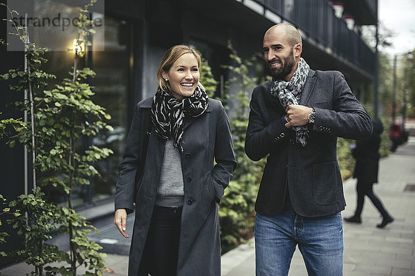 Lächelnder Geschäftsmann und Geschäftsfrau im Gespräch auf dem Bürgersteig