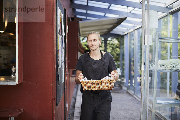 Mittlerer Erwachsener Kellner mit Korb im Cafe