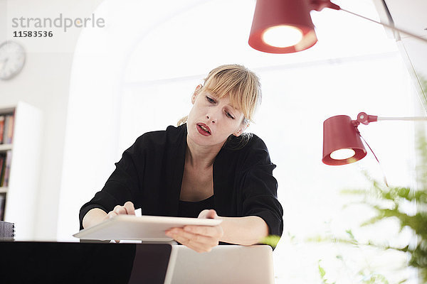 Mittlere erwachsene Geschäftsfrau mit digitalem Tisch im Büro