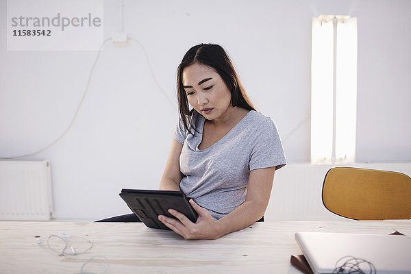 Bloggerin mit digitalem Tablett am Schreibtisch im Büro