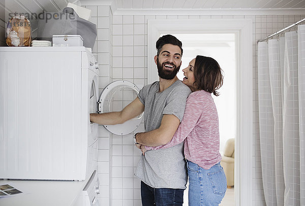 Glückliches Paar steht an der Waschmaschine zu Hause