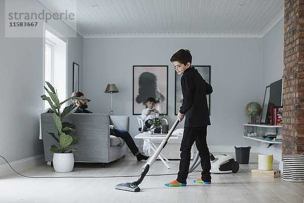 Boy Staubsaugen Boden im Wohnzimmer zu Hause