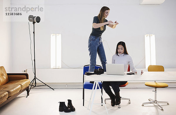 Blogger fotografiert Kollegen mit Laptop am Schreibtisch im Büro