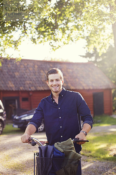 Porträt eines lächelnden Mannes mit Fahrrad im Hinterhof