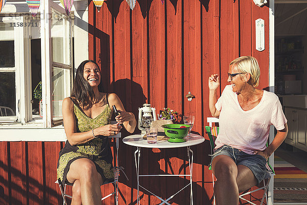 Fröhliche reife Freundinnen genießen den Sommer im Garten an sonnigen Tagen.