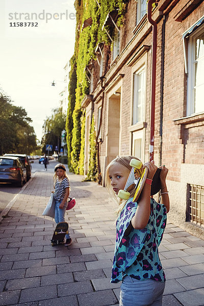 Mädchen mit Skateboards auf dem Bürgersteig beim Bauen in der Stadt