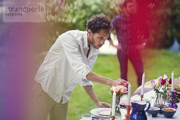 Junger Mann beim Anzünden von Kerzen auf dem Tisch bei der Gartenparty