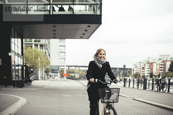Lächelnde Geschäftsfrau mit dem Fahrrad auf der Stadtstraße