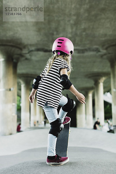 Rückansicht des Mädchens beim Stunt mit Skateboard im Park