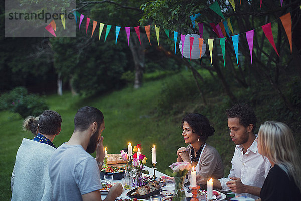 Glückliche Freunde  die sich beim Essen auf der Gartenparty unterhalten.