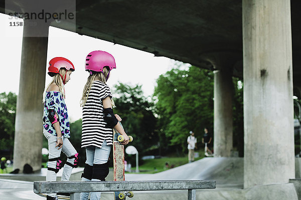 Freunde mit Helmen und Sicherheitspolstern im Skateboardpark