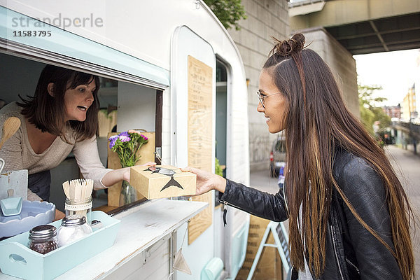 Seitenansicht der Frau  die Lebensmittel von der Besitzerin am Food-Truck kauft.