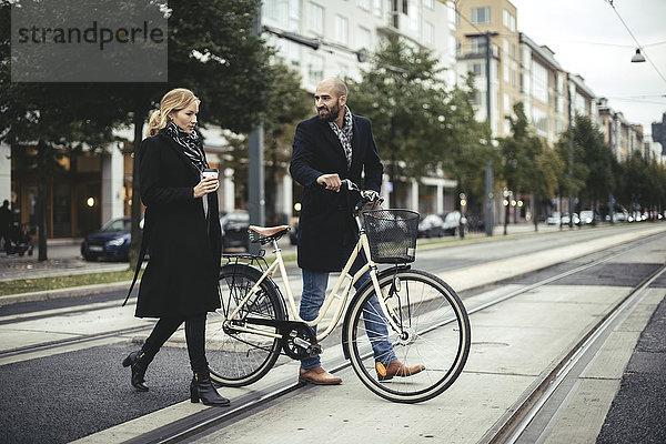 Volle Länge der Geschäftsleute mit Fahrrad über die Stadtstraße