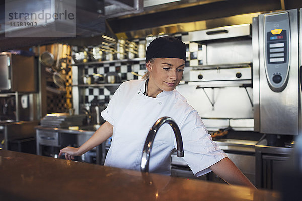 Junge Köchin in der Küche des Restaurants