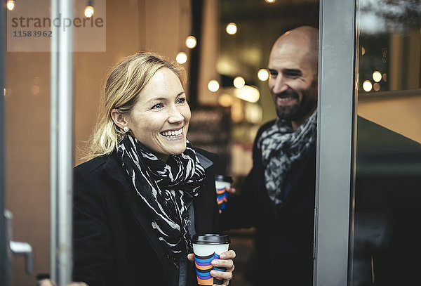 Lächelnde mittlere erwachsene Geschäftsfrau und Geschäftsmann beim Verlassen des Cafés