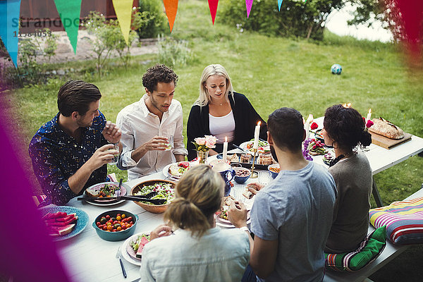 Hochwinkelansicht von Freunden beim Abendessen auf der Gartenparty