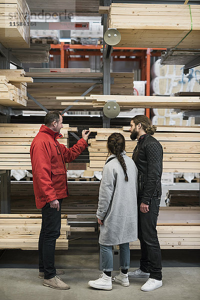 Verkäufer hilft dem Paar beim Kauf von Holzbohlen im Baumarkt