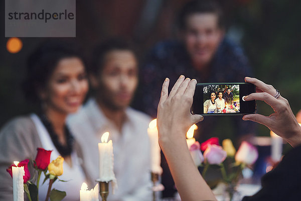 Abgeschnittenes Bild von einer Frau  die Freunde auf einer Gartenparty fotografiert.