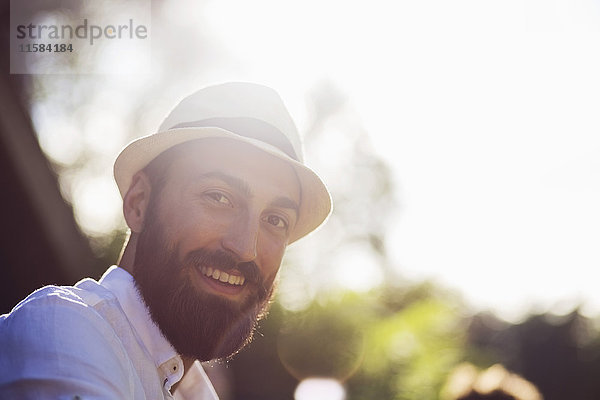 Porträt eines glücklichen Mannes mit Filzhut an einem sonnigen Tag.