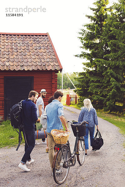 Freunde mit Gepäck und Fahrrad zu Fuß auf der Straße durch Hütte