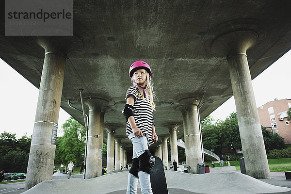 Tiefblick auf das selbstbewusste Mädchen mit Skateboard im Park