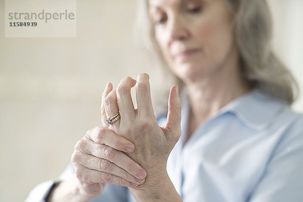 Ältere Frau hält schmerzhafte Hand.