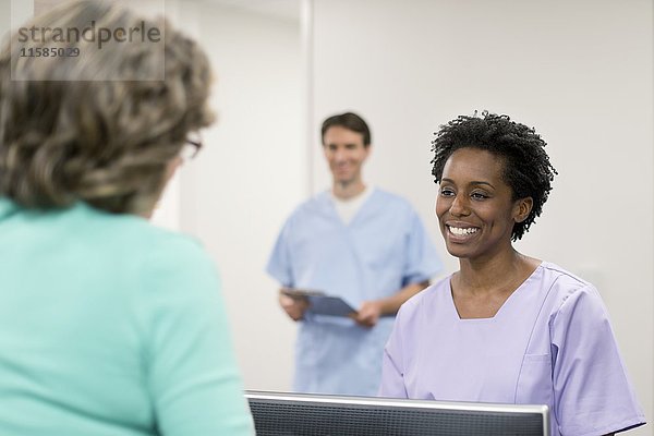 Krankenschwester lächelt einer Patientin zu.