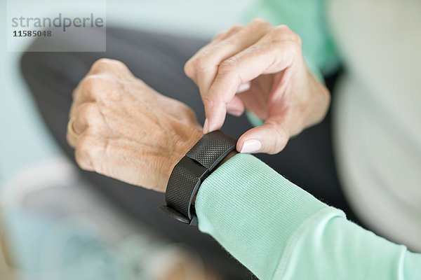 Ältere Frau mit Fitness-Tracker am Handgelenk.