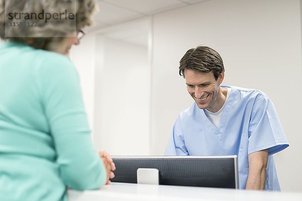 Krankenpfleger am Computer mit einer Patientin.