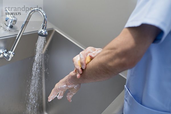 Ein Arzt reinigt sich im Krankenhaus die Hände mit Wasser und Seife.