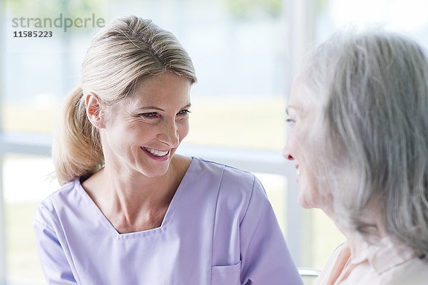 Ältere Frau und reife Frau lächeln sich gegenseitig zu.