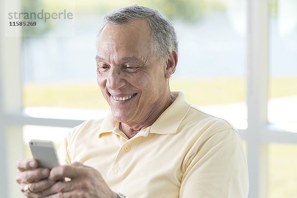 Ein älterer Mann benutzt ein Mobiltelefon.