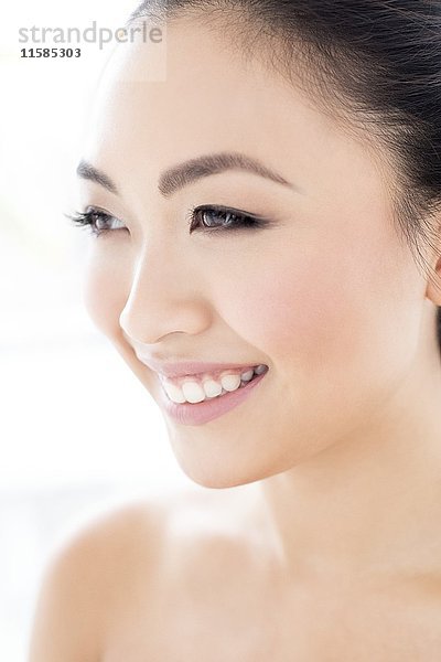 MODELL FREIGEGEBEN. Junge asiatische Frau schaut lächelnd weg  Porträt.
