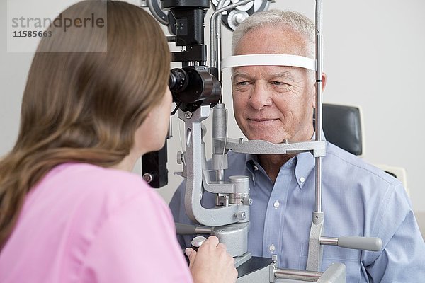 Optikerin testet die Sehkraft eines älteren Mannes.