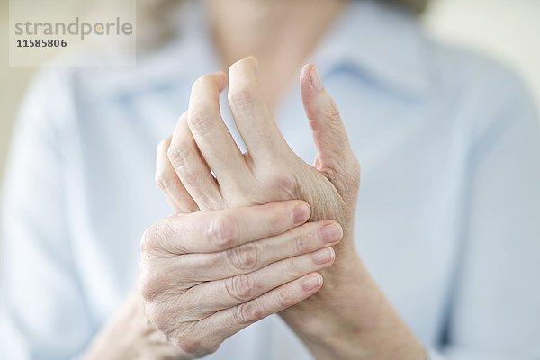 Ältere Frau hält schmerzhafte Hand.