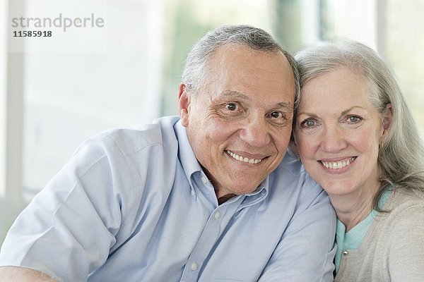 Porträt eines älteren Paares  das in die Kamera lächelt.