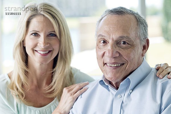 Älterer Mann und reife Frau lächeln in die Kamera.