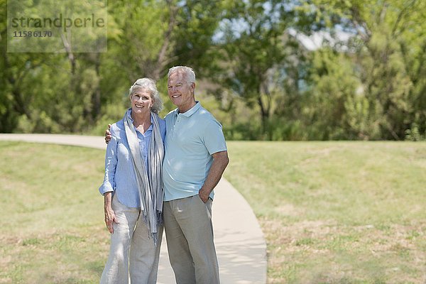 Älteres Paar steht lächelnd im Park.