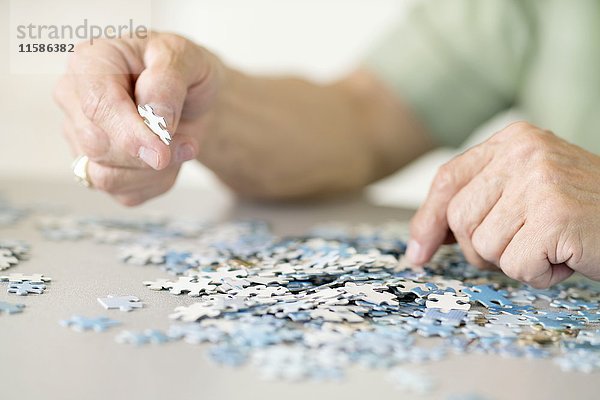 Ein älterer Mann puzzelt ein Puzzle.