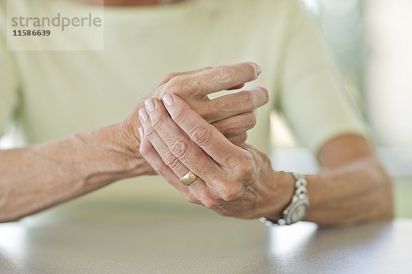 Ältere Frau reibt sich die schmerzende Hand.