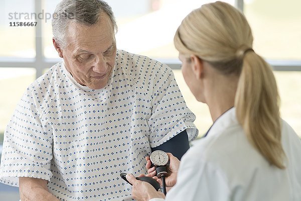 Eine Ärztin misst den Blutdruck eines älteren Mannes.