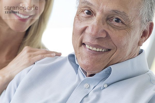 Älterer Mann und reife Frau lächeln in die Kamera.