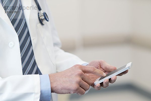 Männlicher Arzt mit Smartphone.