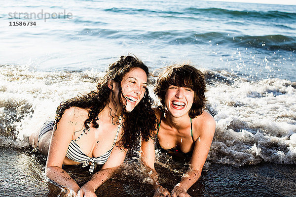 Frauen spielen in Wellen am Strand